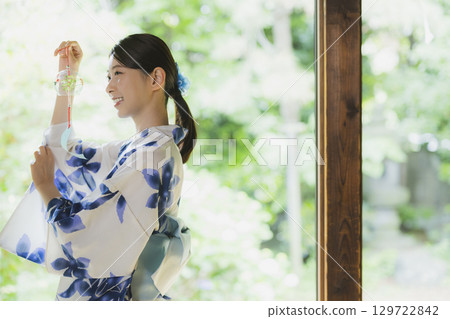 A woman in a yukata holding a wind chime on the porch A woman in a yukata holding a wind chime on the porch 129722842