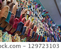 Side view Slippers or sandals of many colors hung from street stalls in Marrakech's souk 129723103