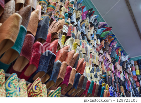 Side view Slippers or sandals of many colors hung from street stalls in Marrakech's souk 129723103