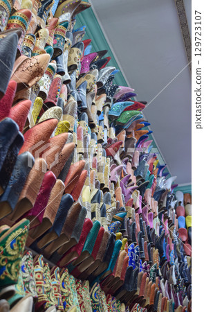 Vertical view Slippers or sandals of many colors hung from street stalls 129723107