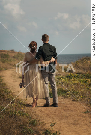 young couple in love walking along the road to the sea 129724010