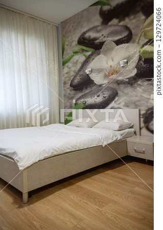 Double bed with pillows and light from the window. 129724066