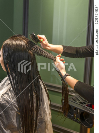 In a beauty salon, a client girl's hair is washed. 129724084