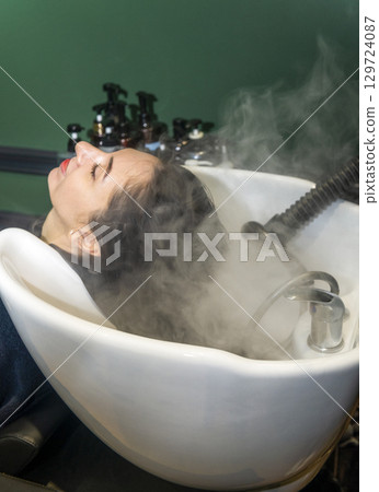 In a beauty salon, a girl's hair is washed and treated In a beauty salon, a girl's hair is washed and treated 129724087