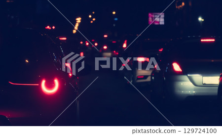 Abstract environment of traffic jam on the road at night. Rear side of car with turn on light. Red glow of car taillights shines brightly at night. 129724100