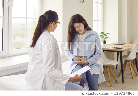 Pregnant woman with abdomen pain visiting her female obstetrician doctor in maternity clinic. 129724965