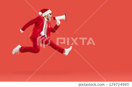 Old man in Santa style, Xmas cap jumping hurrying up screaming loudspeaker in air on red background. Old man in Santa style, Xmas cap jumping hurrying up screaming loudspeaker in air on red background. 129724993