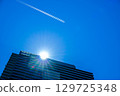 一架客機和尾跡飛過一棟高層公寓大樓 129725348