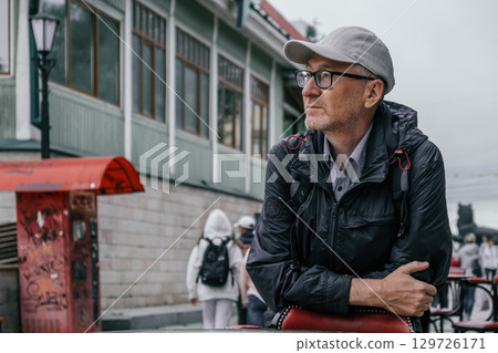 man in casual attire enjoys quiet moment in bustling street with shops. closeup. 129726171