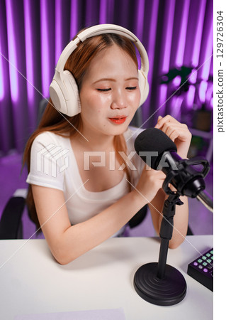 Podcast host recording professional audio for streaming broadcast and digital content creation in modern studio Podcast host recording professional audio for streaming broadcast and digital content creation in modern studio 129726304
