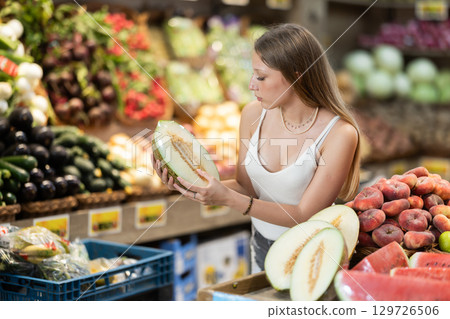 Young woman choosing a melon in a fruit store 129726506