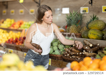 Young woman shopping in vegetable store and buy cassava Young woman shopping in vegetable store and buy cassava 129726514