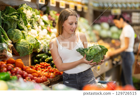 Woman choosing green cabbage in grocery store Woman choosing green cabbage in grocery store 129726515