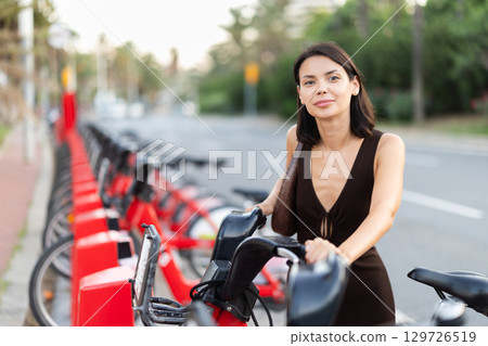 Girl parks bicycle at parking spot 129726519