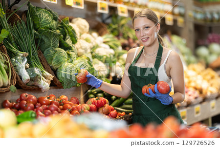 female seller lays out tomatoes on the counter 129726526