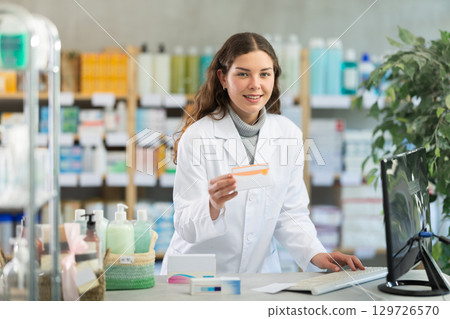 Portrait of female pharmacist working in modern drugstore and offering to buy pills Portrait of female pharmacist working in modern drugstore and offering to buy pills 129726570
