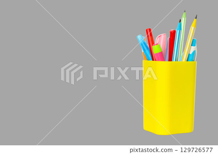 Colorful pens and pencils stand in a vibrant yellow holder Colorful pens and pencils stand in a vibrant yellow holder 129726577