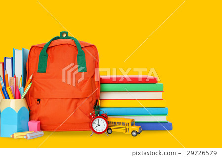 School supplies are organized beside a bright yellow backdrop 129726579