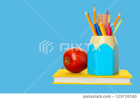 A bright scene featuring school supplies and an apple on a desk A bright scene featuring school supplies and an apple on a desk 129726580
