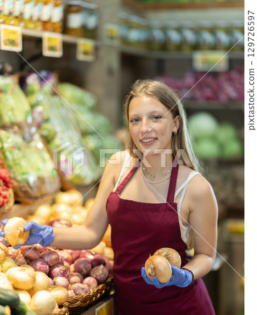 Woman seller putting onions on display case Woman seller putting onions on display case 129726597