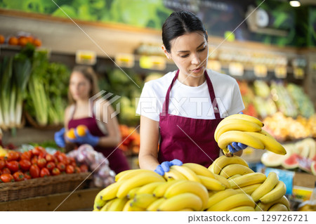 Woman seller putting bananas on the counter 129726721