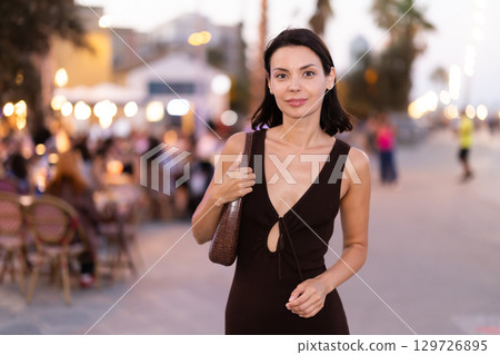 Smiling girl walks around old city district Barceloneta, pedestrian promenade embankment. 129726895