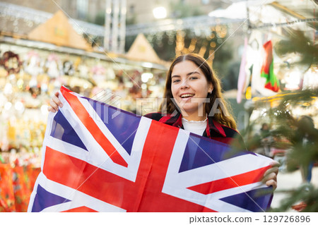 Young woman waving the United Kingdom flag at New Year street fair 129726896