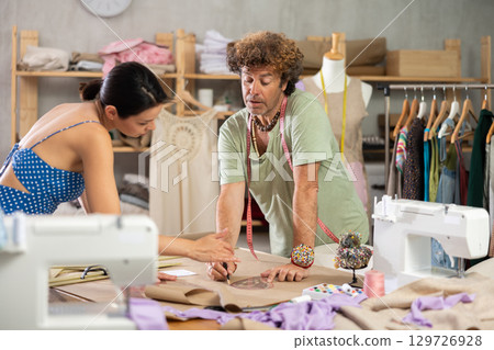 Woman and man tailor draw dress pattern with curve ruler on paper 129726928