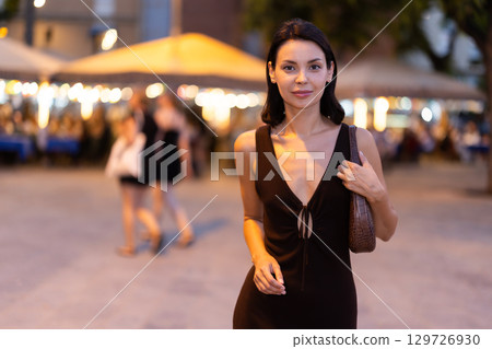 In evening, smiling girl walks around old city district Barceloneta, in vicinage of Passeig Nou 129726930