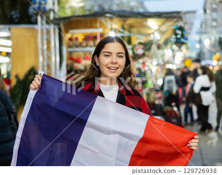 Happy girl with French flag in street Christmas fair Happy girl with French flag in street Christmas fair 129726938