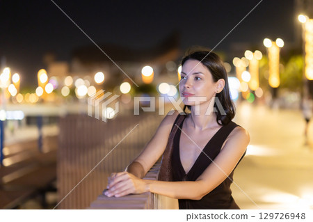 At night, smiling girl walks around old city district Barceloneta, in vicinage of Citadel Park 129726948
