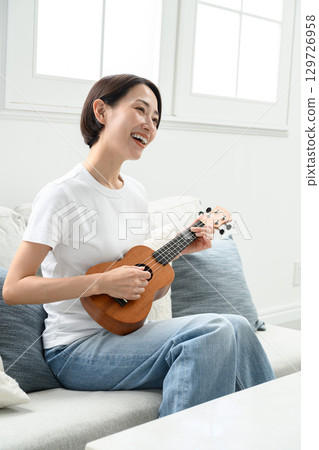 一個女人在玩夏威夷四弦琴 一個女人在玩夏威夷四弦琴 129726958