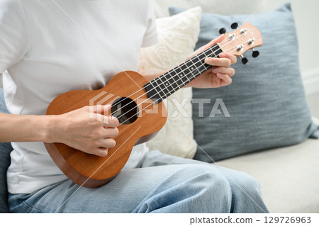 A woman playing an ukulele 129726963