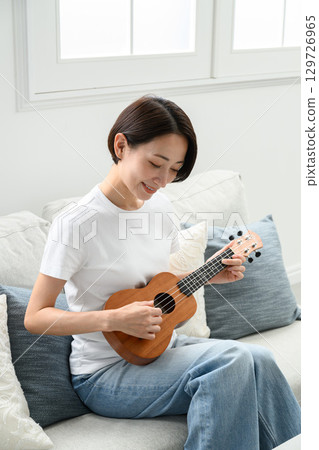 A woman playing an ukulele 129726965