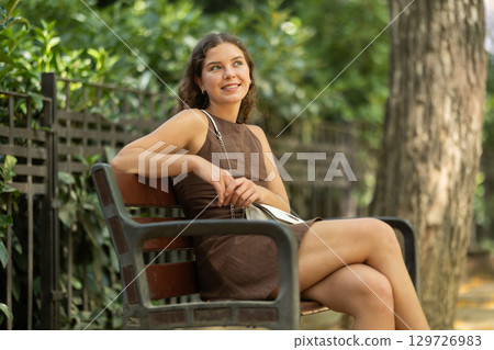 Young woman sitting on a bench in a European city 129726983