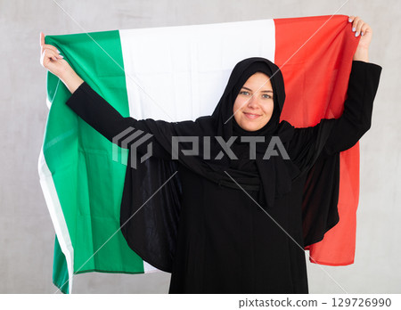 Happy young woman dressed in traditional islamic clothes with italian flag Happy young woman dressed in traditional islamic clothes with italian flag 129726990