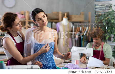 Female dressmaker applying textile on woman Female dressmaker applying textile on woman 129727131