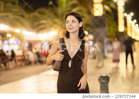 Woman walking along coastal promenade at night in Barcelona Woman walking along coastal promenade at night in Barcelona 129727144