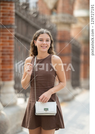 Young woman traveler in summer dress with handbag enjoying walk near columns of architectural complex of Hospital de la Santa Creu i Sant Pau in Barcelona on spring day 129727191