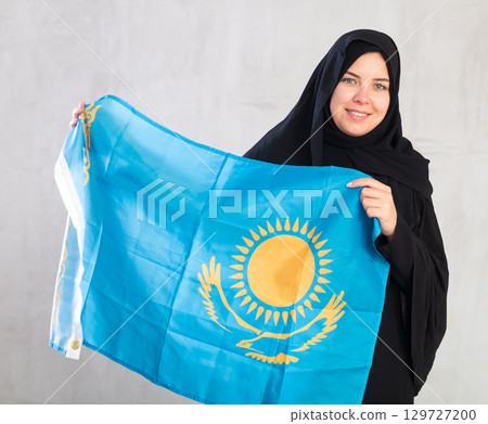 Happy young woman dressed in traditional islamic clothes with kazakh flag Happy young woman dressed in traditional islamic clothes with kazakh flag 129727200