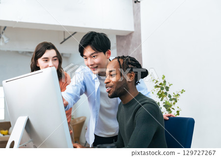 跨國人士在辦公室一邊看著電腦一邊交談 跨國人士在辦公室一邊看著電腦一邊交談 129727267