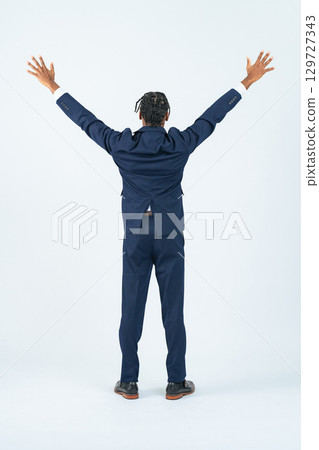 Full-body photo of a black male businessman raising his arms in a cheer 129727343