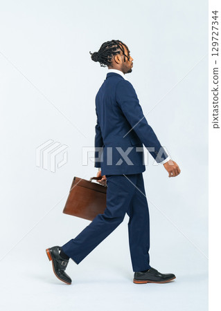 Full body photo of a walking black male business person Full body photo of a walking black male business person 129727344