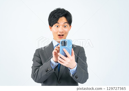A male business person is surprised at his smartphone A male business person is surprised at his smartphone 129727365