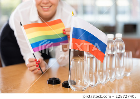 Unrecognizable girl sets midget flags of Russia and LGBT before international negotiations 129727403