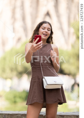 Woman walking around town and holding mobile phone Woman walking around town and holding mobile phone 129727439