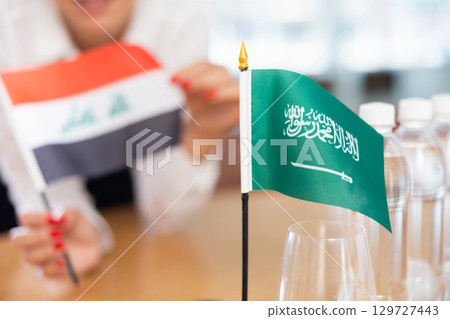 Flags of Iraq and Saudi Arabia stand on negotiating table in office 129727443