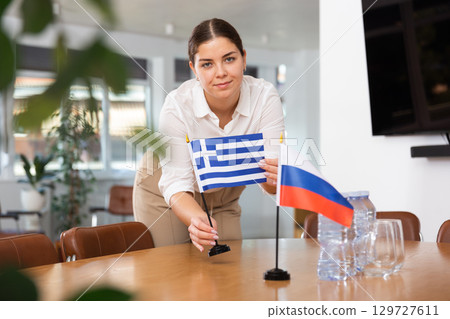Young woman puts flags of Greece and Russia on table Young woman puts flags of Greece and Russia on table 129727611