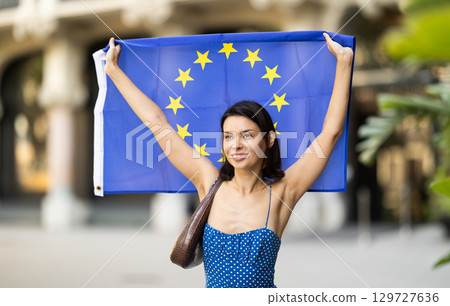 Girl waving European Union flag on street of summer city Girl waving European Union flag on street of summer city 129727636