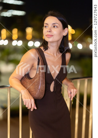 At night, smiling girl walks around old city district Barceloneta, in vicinage of Citadel Park 129727643